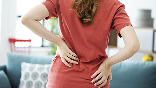 Woman holding lower back in pain before visiting Boise chiropractor